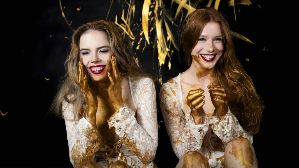 Farbshooting Goldfarbe – zwei Modelle lachend mit Goldsplash, ausgelassene Freude, Studio Hitzkirch Luzern – Snapshot.style